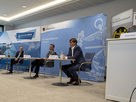In einem der Panels diskutierten der ehemalige Wehrbeauftragte Hans-Peter Bartels (l.), der Bundesvorsitzende Oberstleutnant André Wüstner (2.v.r.)  und der Historiker Prof. Sönke Neitzel (r.), moderiert vom ARD-Korrespondenten Stephan Stuchlik. Rechts am Rednerpult: Generalleutnant Bernd Schütt, Abteilungsleiter Strategie und Einsatz im BMVg. Foto: DBwV/Yann Bombeke