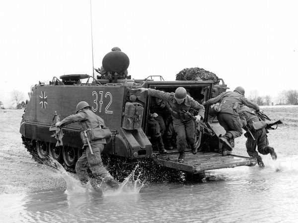 Soldaten springen aus einem M113-Transportpanzer.