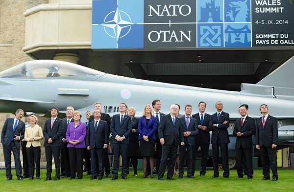 Staats- und Regierungschefs stehen vor einem Typhoon-Kampfjet und beobachten den Vorbeiflug eines Militärflugzeugs während des NATO-Gipfels 2014 im Celtic Manor Resort in Newport, Wales, am 5. September 2014. Foto: picture alliance/dpa/Facundo Arrizabalaga