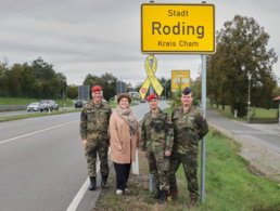Oberstleutnant Dr. Tobias Gößlbauer (v.l.n.r.), Bürgermeisterin Alexandra Riedl, Oberstleutnant Thomas Zimmermann und Stabsfeldwebel Christian Schleicher bei der Übergabe der Gelben Schleife am Rodinger Ortsschild an der B85. Foto: Marco Schultz