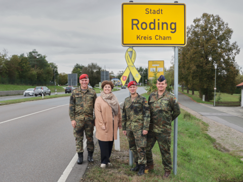 Oberstleutnant Dr. Tobias Gößlbauer (v.l.n.r.), Bürgermeisterin Alexandra Riedl, Oberstleutnant Thomas Zimmermann und Stabsfeldwebel Christian Schleicher bei der Übergabe der Gelben Schleife am Rodinger Ortsschild an der B85. Foto: Marco Schultz