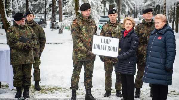 Oberstleutnant Peter Papenbroock (M.), Oberstleutnant René Braun (4.v.r), Ursula von der Leyen und Dalia Grybauskaite (r), Präsidentin der Republik Litauen, halten in der Nato-Kaserne in Rukla, Litauen, ein Schild mit der Aufschrift "Camp Adrian Rohn". Sie gedenken dem Soldaten, der hier 2018 bei einer Übung ums Leben kam. Foto: dpa