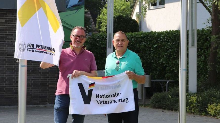 Bernhard Esch (l.), Erster Beigeordneter der Stadt Lohmar und Rudolf Schmelzer, Ehrenmitglied des Deutschen BundeswehrVerbandes, hissen vor dem Rathaus die Flagge zum Nationalen Veteranentag am 15. Juni. Foto: Stadt Lohmar