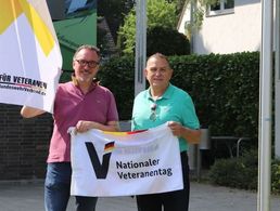 Bernhard Esch (l.), Erster Beigeordneter der Stadt Lohmar und Rudolf Schmelzer, Ehrenmitglied des Deutschen BundeswehrVerbandes, hissen vor dem Rathaus die Flagge zum Nationalen Veteranentag am 15. Juni. Foto: Stadt Lohmar