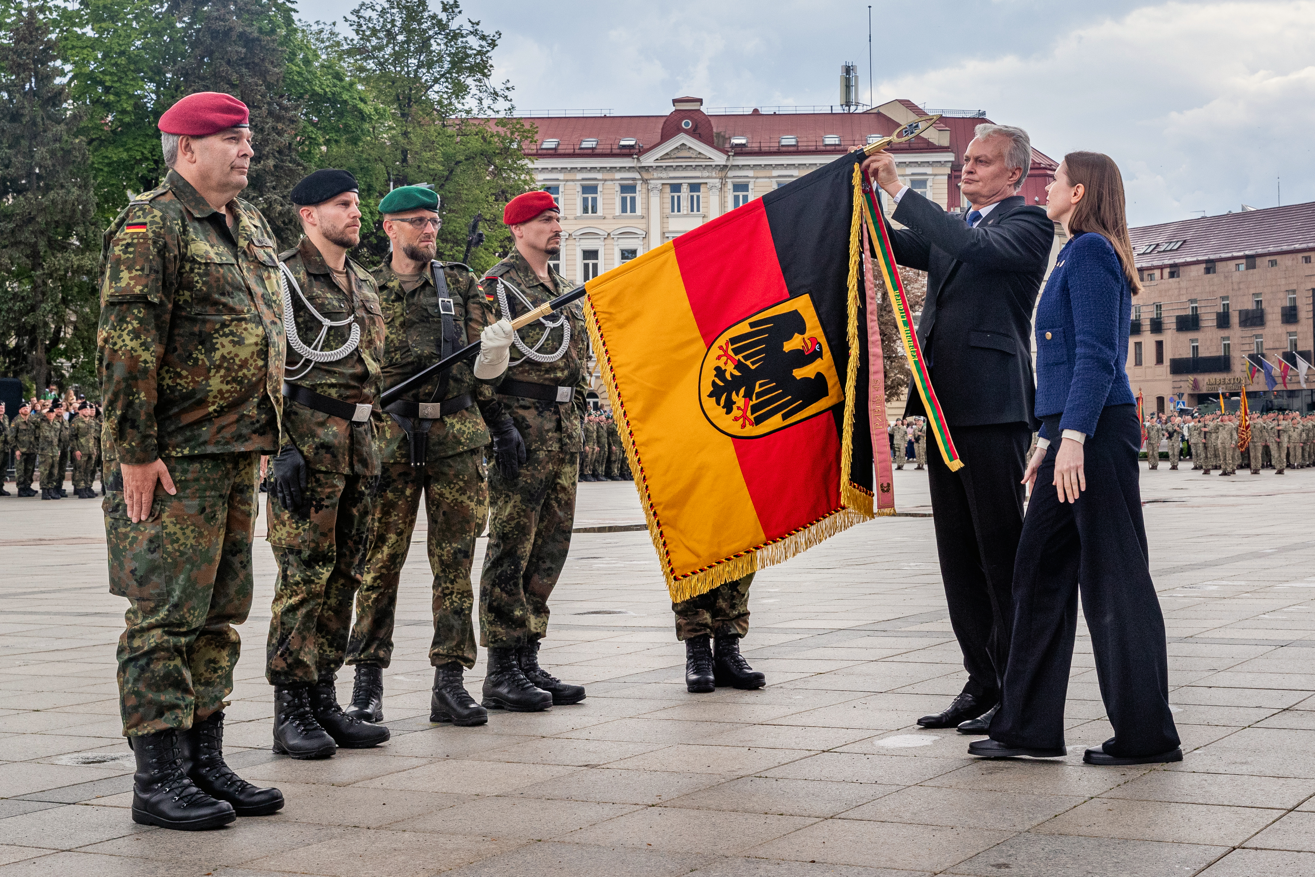 Der litauische Präsident Gitanas Nauseda und Verteidigungsministerin Dovile Šakaliene befestigen das Fahnenband an der Truppenfahne der neu aufgestellten Brigade beim Aufstellungappell. Foto: Bundeswehr/Mario Bähr